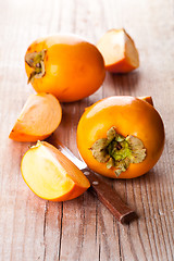 Image showing fresh sliced persimmons and knife 