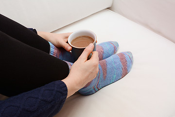 Image showing Woman's hands holding a hot beverage, sitting on a couch