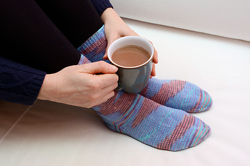 Image showing Woman holding a hot drink, wearing warm knitted socks