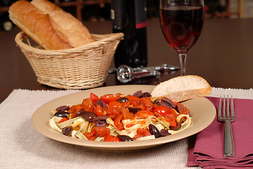 Image showing A plate of pasta puttanesca with wine and bread