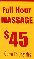 Image showing A yellow and red sign advertising hour long massages