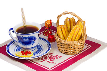 Image showing Cup of tea , candies and cakes in a wicker basket.