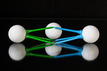 Image showing White golf balls and different colored tees