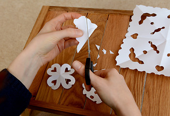 Image showing Woman making paper snowflakes at a wooden craft table