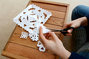 Image showing Woman cutting paper into snowflake designs