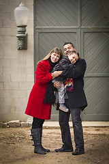 Image showing Warmly Dressed Family Loving Son in Front of Rustic Building