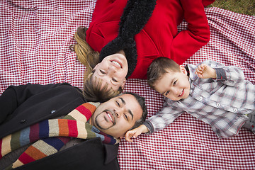 Image showing Family in Winter Clothing Laying on Their Backs in Park