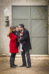 Image showing Warmly Dressed Family Loving Son in Front of Rustic Building