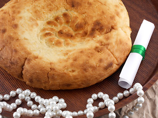 Image showing Home bakery, bread on wooden plate with pearls and invitation card