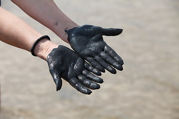 Image showing hands in black mud