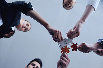 Image showing Group of business people assembling jigsaw puzzle