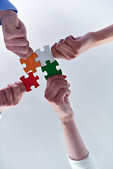 Image showing Group of business people assembling jigsaw puzzle