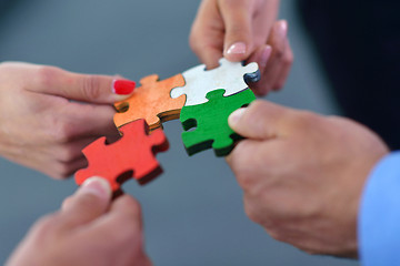 Image showing Group of business people assembling jigsaw puzzle