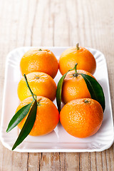 Image showing tangerines with leaves in plate 