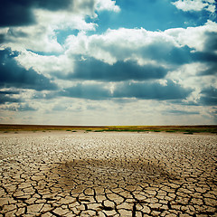 Image showing wet spot on cracked earth under dramatic sky