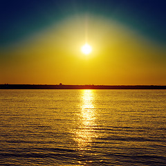 Image showing orange sunset over dark water