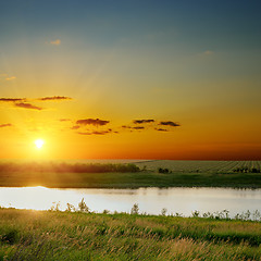 Image showing orange sunset over river with green sides