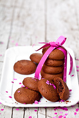 Image showing plate of fresh chocolate cookies with pink ribbon and confetti 