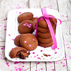 Image showing plate of fresh chocolate cookies with pink ribbon and confetti 