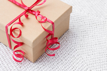 Image showing Gift with red ribbon on a knitted background