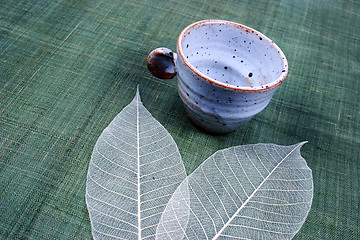 Image showing Pottery cup and pretty spring leaves
