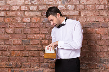 Image showing Man reading a document from a wooden box