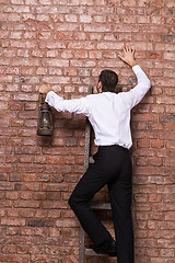 Image showing Man up against a brick wall