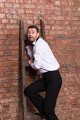 Image showing Terrified man trapped at the top of a ladder