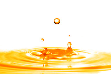 Image showing drop falling into orange water with splash isolated on white