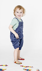 Image showing child with painted feet holding trousers