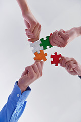 Image showing Group of business people assembling jigsaw puzzle