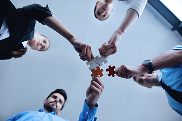 Image showing Group of business people assembling jigsaw puzzle