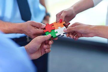 Image showing Group of business people assembling jigsaw puzzle