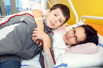 Image showing sad middle-aged woman lying in hospital with son