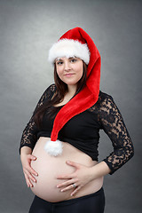 Image showing beautiful pregnant santa woman tenderly holding her tummy