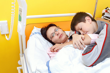 Image showing sad middle-aged woman lying in hospital with son