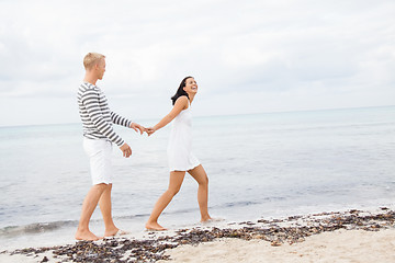 Image showing Couple holding hands while walking on the beach