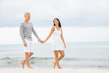 Image showing Couple holding hands while walking on the beach