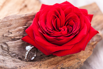 Image showing beautiful ring on wooden background and red rose