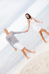 Image showing Couple holding hands while walking on the beach