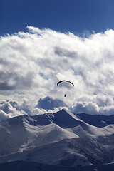 Image showing Winter mountains in evening and silhouette of paraglider