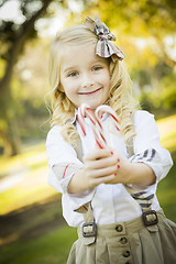 Image showing Cute Little Girl Holding Christmas Candy Canes Outdoors
