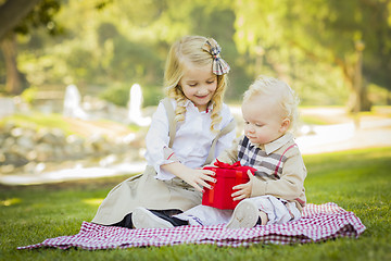 Image showing Little Girl Gives Her Baby Brother A Gift at Park
