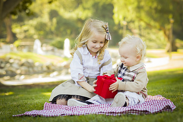 Image showing Little Girl Gives Her Baby Brother A Gift at Park
