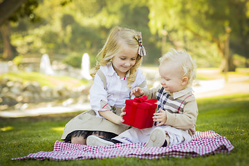 Image showing Little Girl Gives Her Baby Brother A Gift at Park
