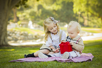 Image showing Little Girl Gives Her Baby Brother A Gift at Park
