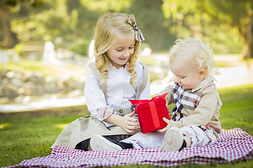 Image showing Little Girl Gives Her Baby Brother A Gift at Park
