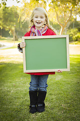 Image showing Cute Girl Holding a Green Chalkboard Wearing Winter Coat Outdoor