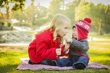 Image showing Little Girl with Baby Brother Wearing Coats and Hats Outdoors
