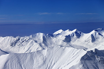 Image showing Off-piste snowy slope at sunny day and multicolor blue sky